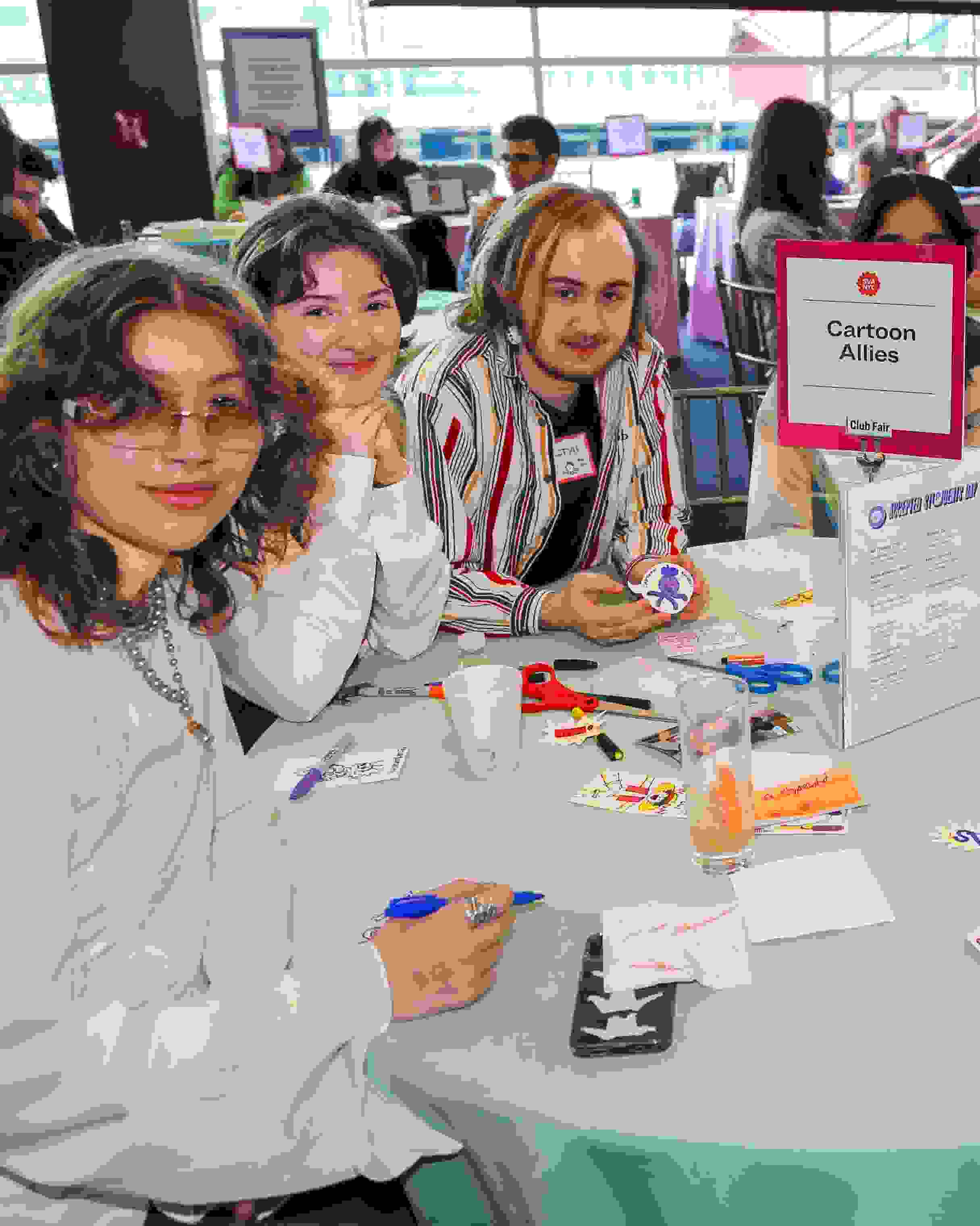 People sitting around a round table at a club fair; a sign in the middle of the table reads “Cartoon Allies”