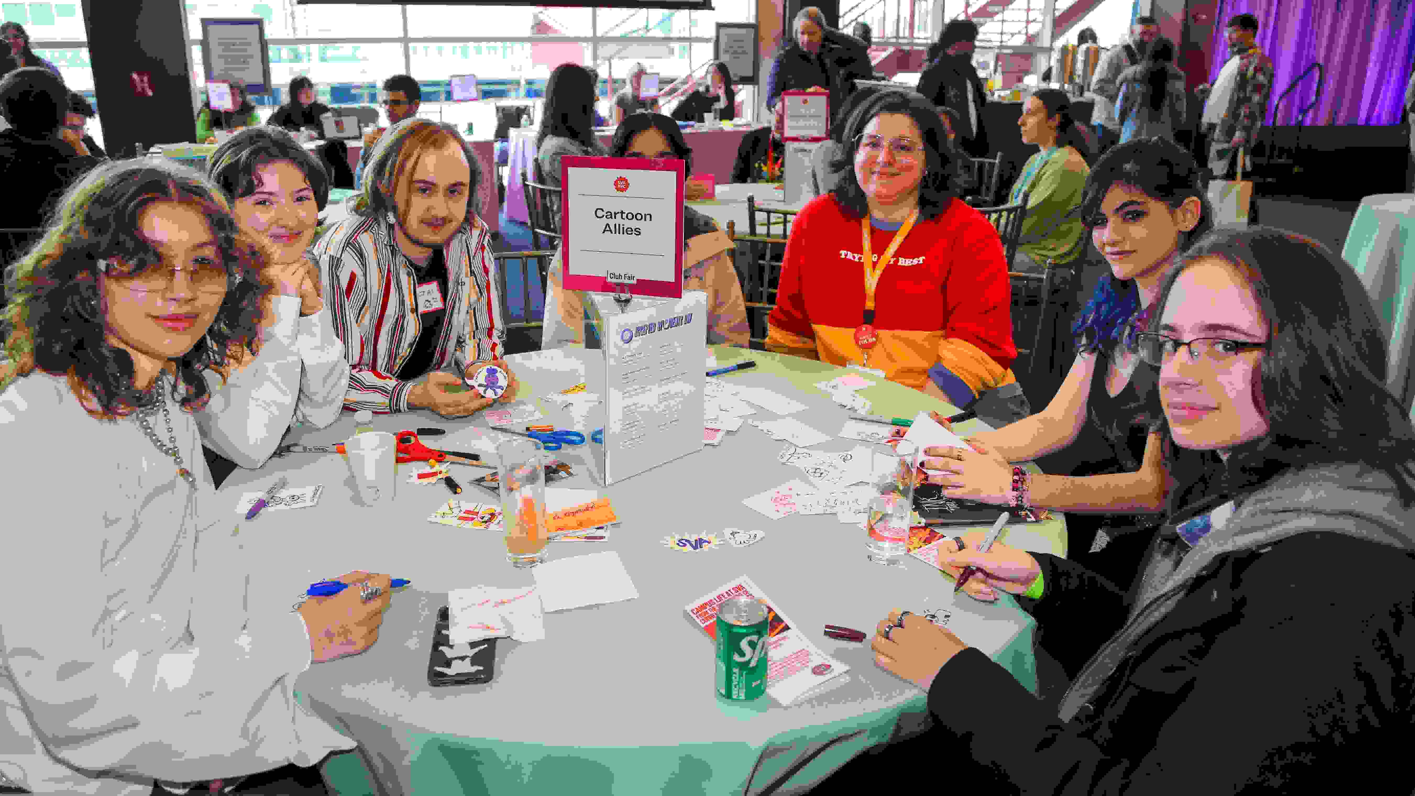 People sitting around a round table at a club fair; a sign in the middle of the table reads “Cartoon Allies”