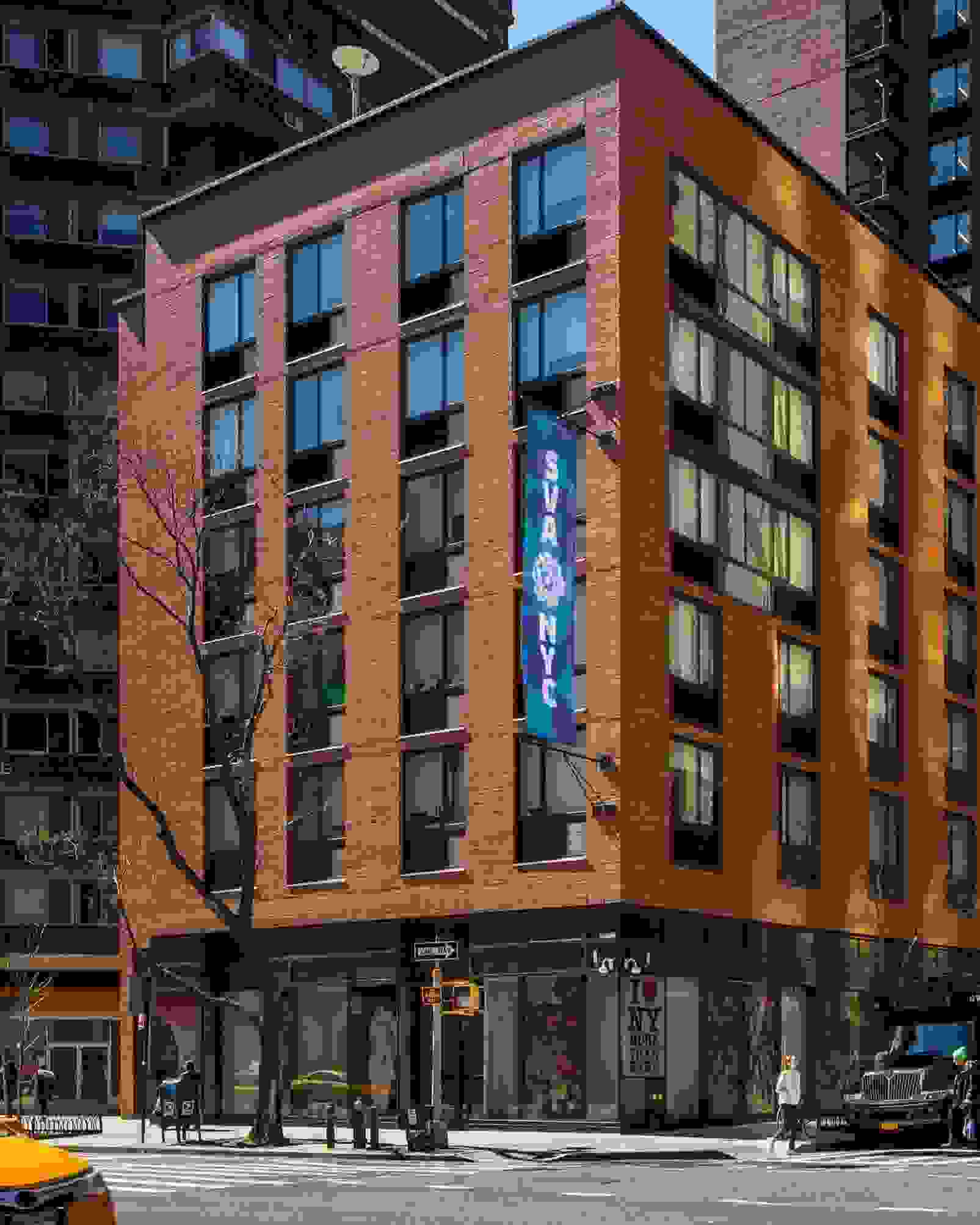 A busy New York City street; a building facade with an ‘SVA’ flag on it.