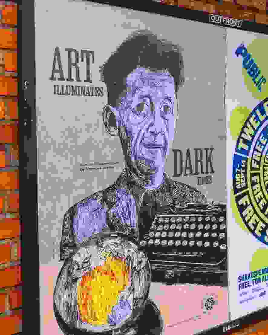 A man strolls past a brick wall adorned with vibrant posters.