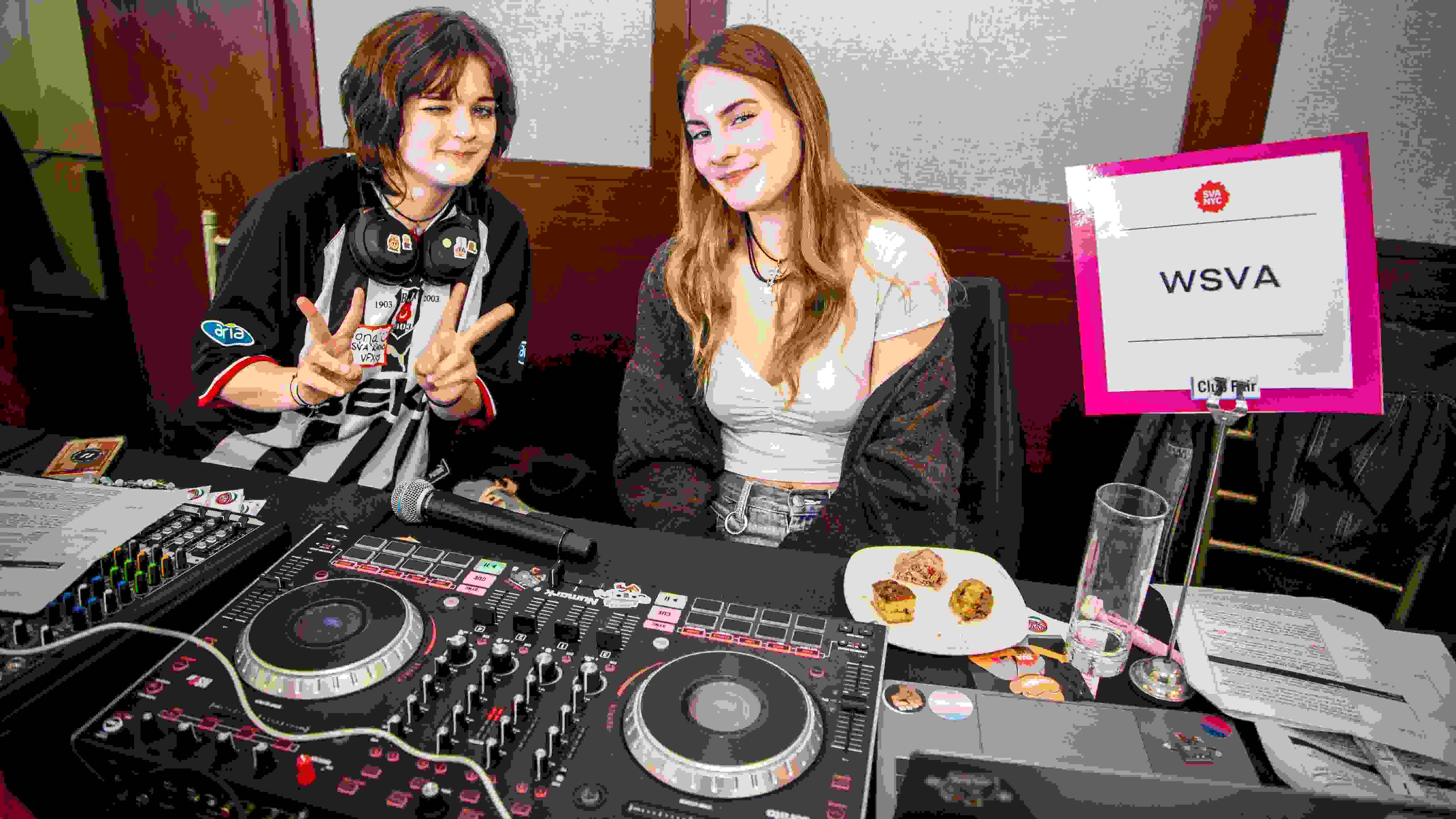 Two people at a club fair pose for a photo with a turntable and sign that says “WSVA.”