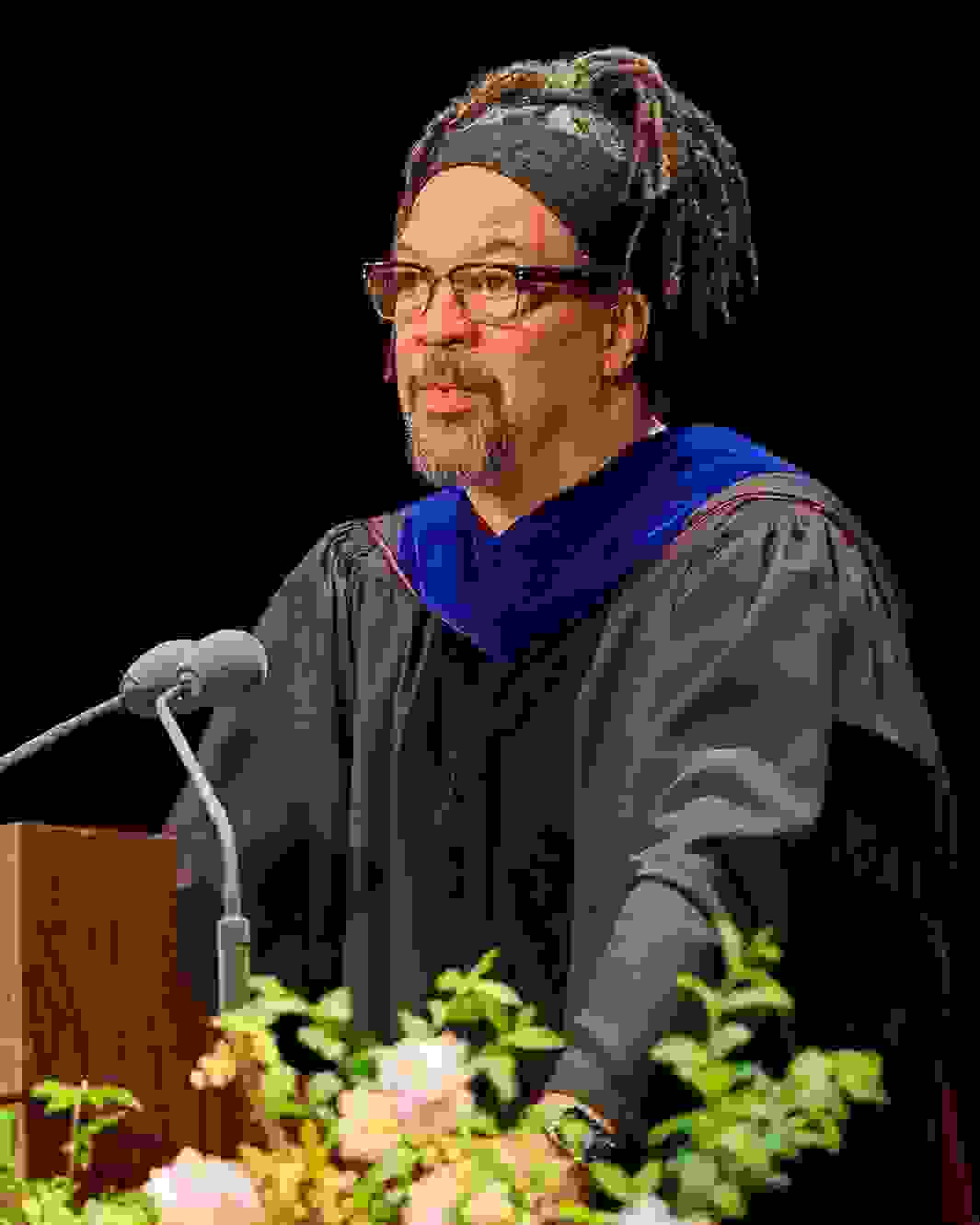 Commencement speaker Gary Simmons speaking on a podium decorated with flowers and the SVA logo