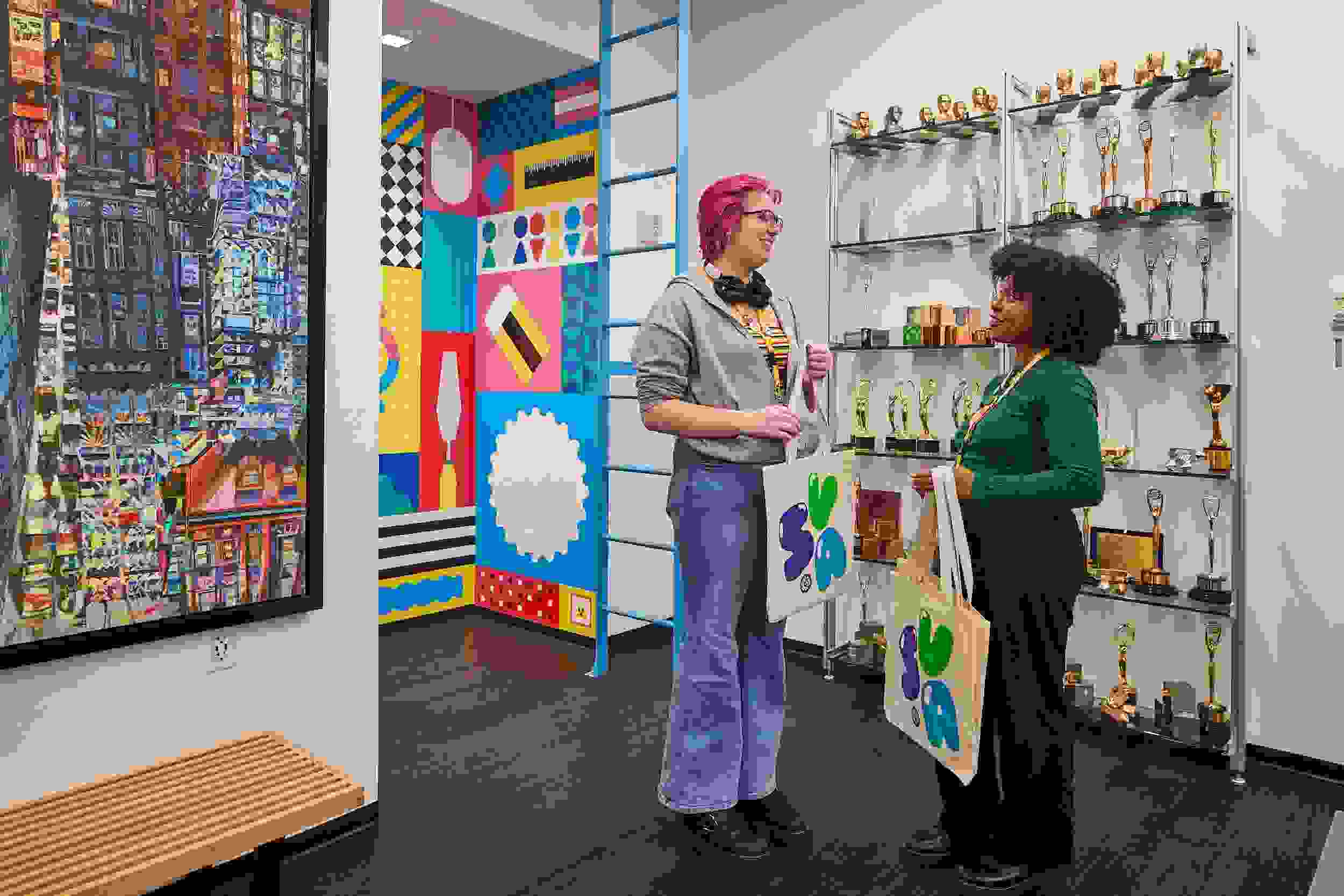 Two students standing by a mural and awards