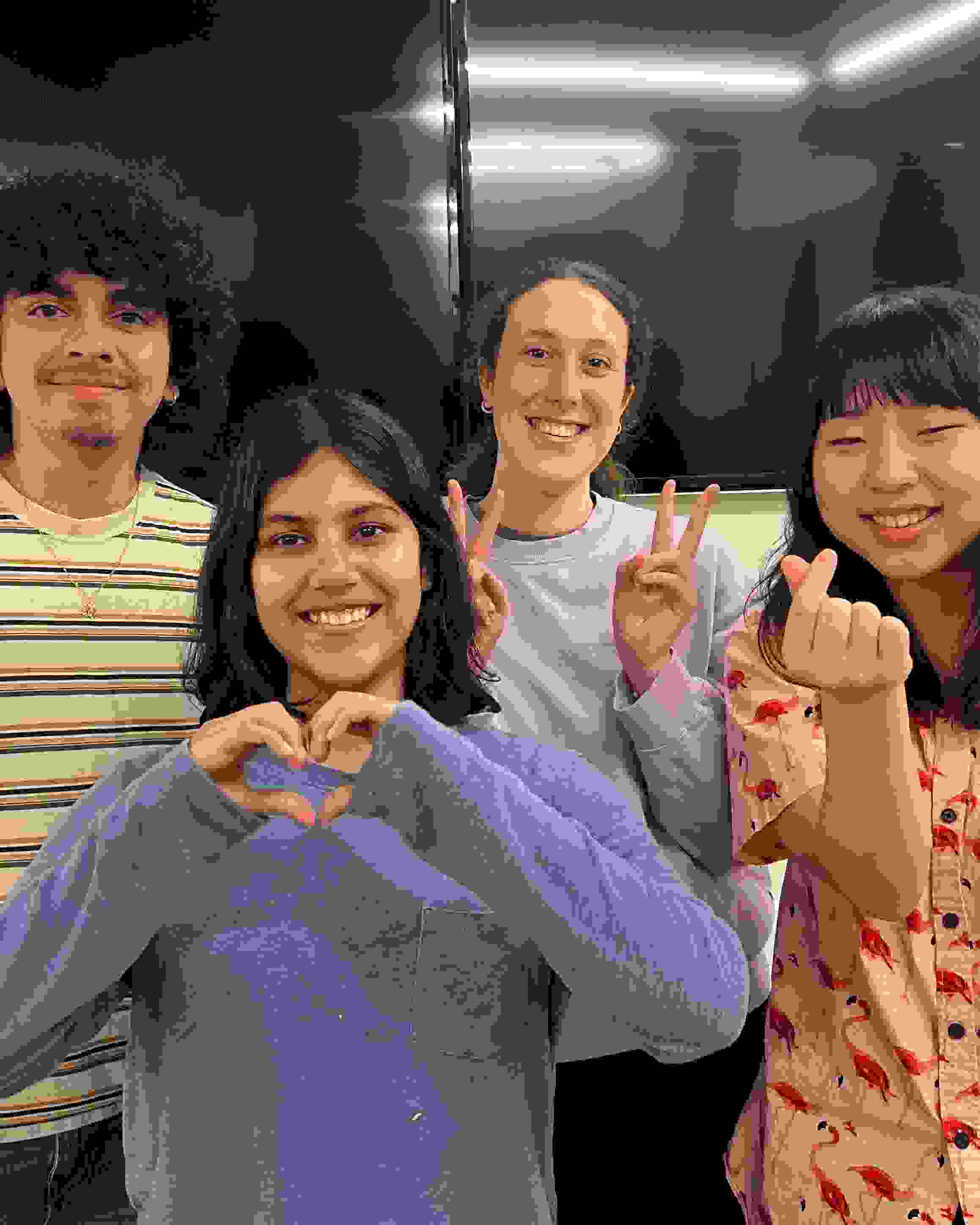 Four VASA officers standing in front of white wall with two mounted tv screens. The officers are giving peace and heart signs with their hands.