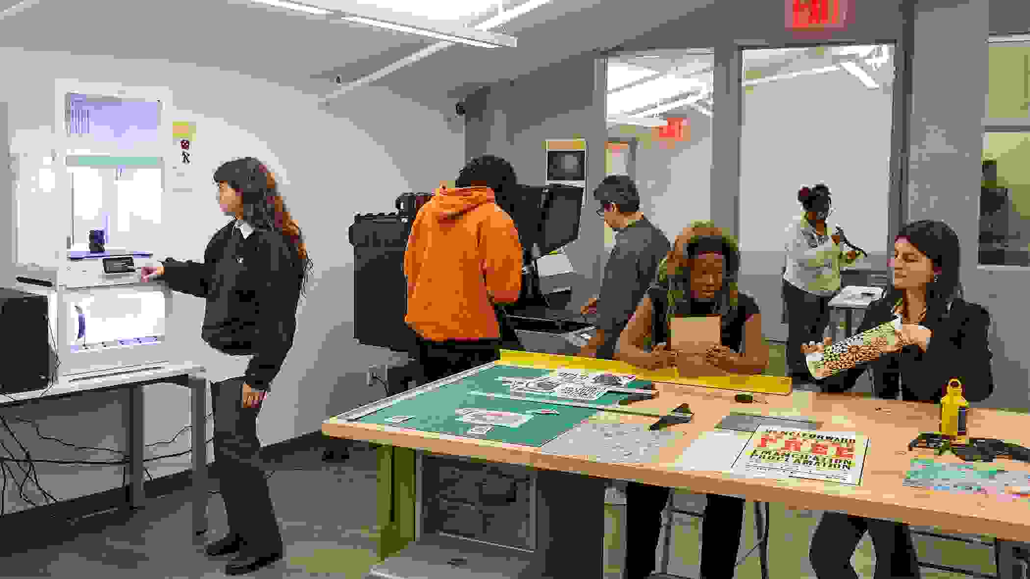 Students and instructors working on various projects in a design fabrication lab.