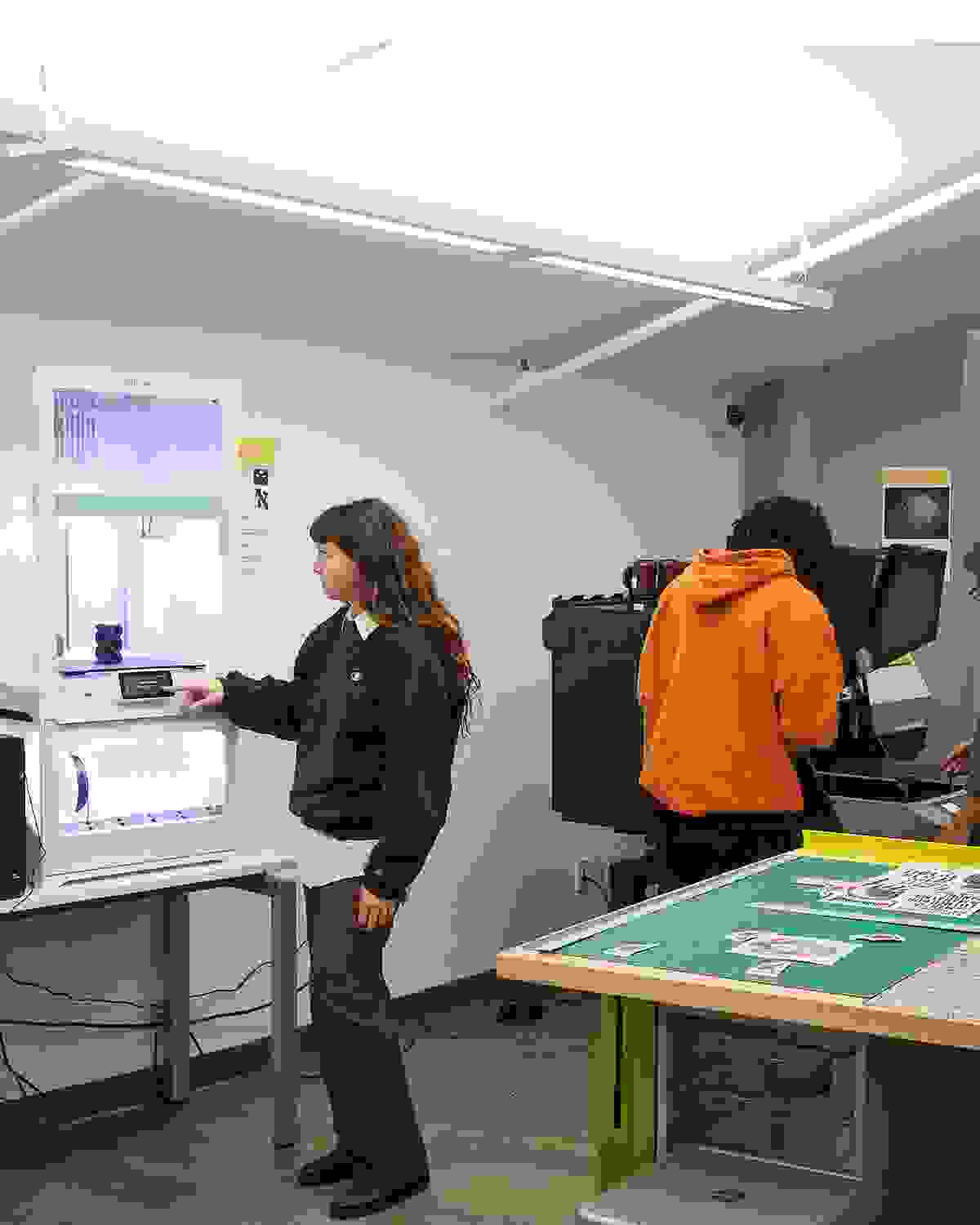 Students and instructors working on various projects in a design fabrication lab.
