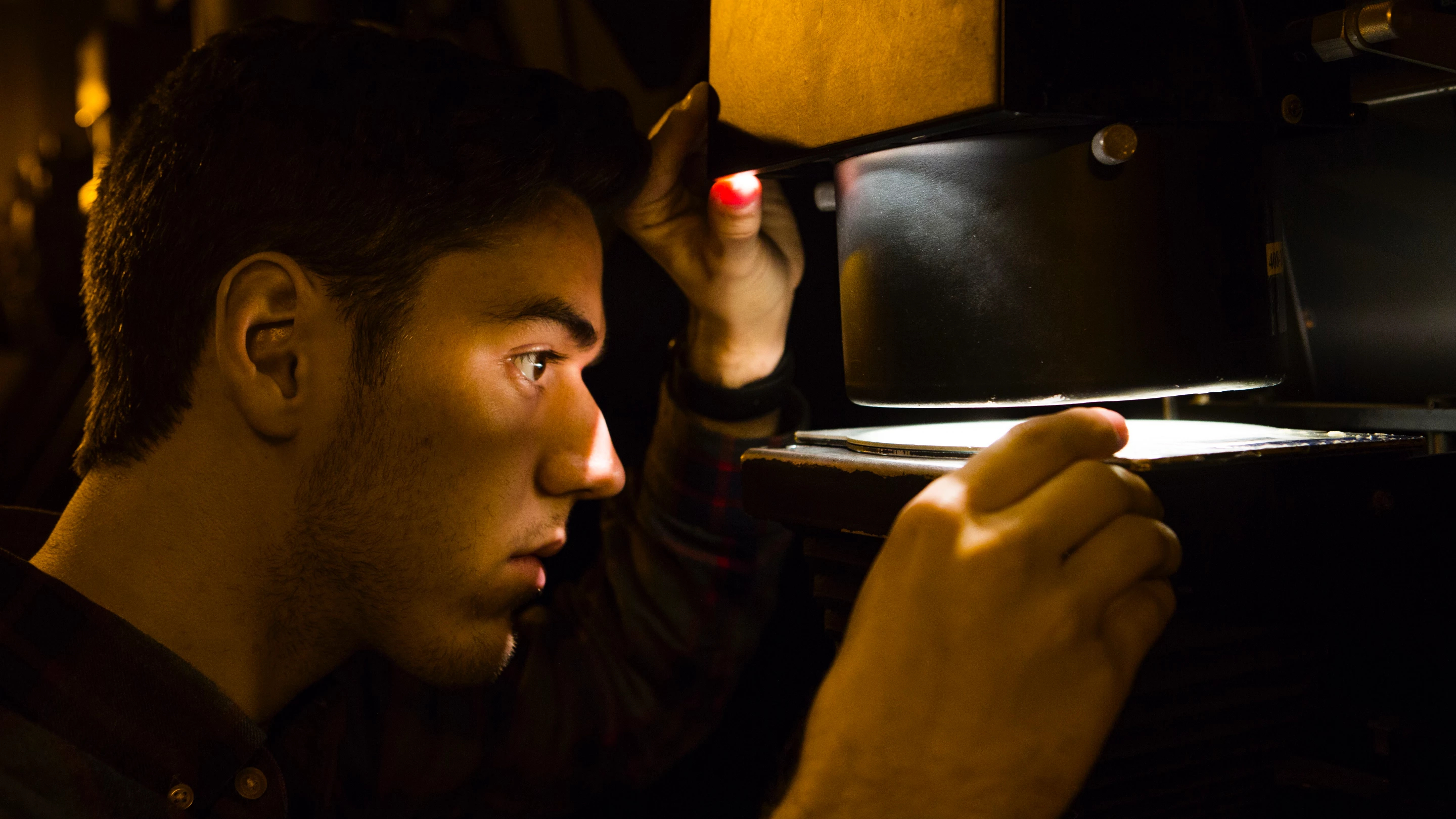 A close up of a person adjusting an image inside of a physical photo enlarger.