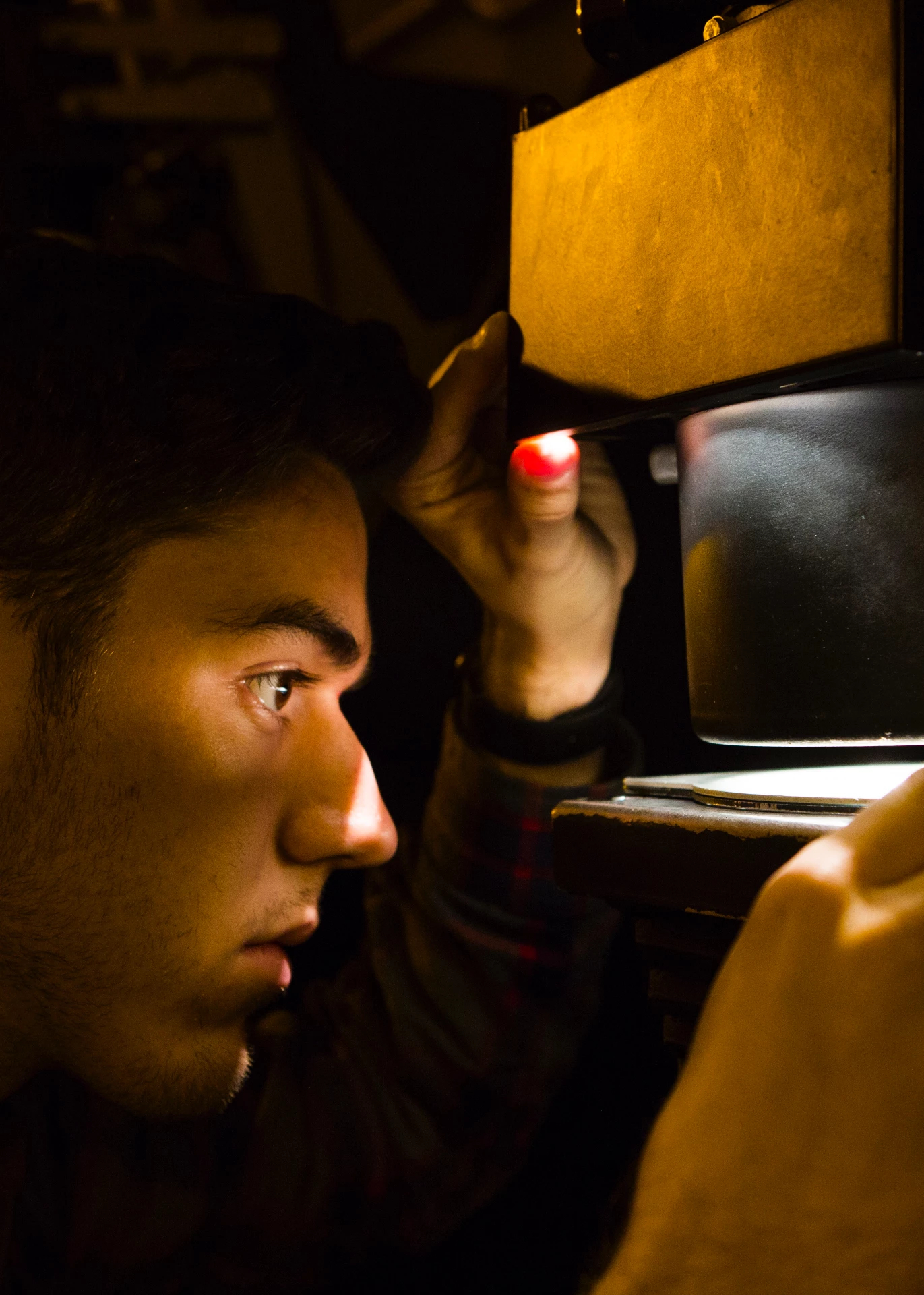 A close up of a person adjusting an image inside of a physical photo enlarger.