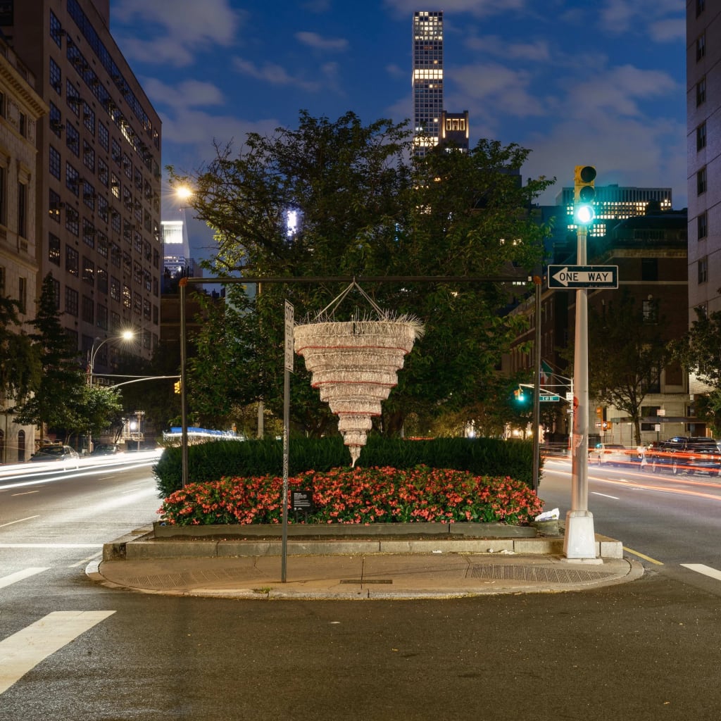 A photograph of the meridian on Park Avenue in Manhattan, which has been decorated with two large chandelier-like hanging sculptures made of empty plastic water bottles.