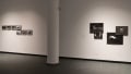 Seven small photographs occupy the wall to the left, and to the right are four dark photographs pinned up.