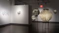 The third gallery with photographs printed on glass on the left wall and paper lanterns on wire pedestals on the right.