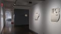 In a hallway of the SVA Chelsea Gallery, flat works hang from the wall on the left side, and sculptural works are seen in the third gallery.