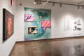 installation shot of framed work, objects on shelves, and a vinyl wall image