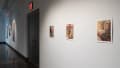 A glimpse of the first gallery space is shown in which three oil paintings are displayed. On the following wall to the right, there are three watercolor pieces hung on the wall.
