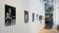 Angled view of the SVA Flatiron Windows hallway facing east; we see a row of large black and white photographic prints with a large monitor in the middle.