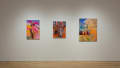 Three brightly colored paintings hang in the center of one wall. One shows a statue of a man among flowers, and in another, a figure bends down to pick a flower in a fenced-in yard.