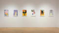 Six colorful poster illustrations hang in a horizontal row in the middle of the wall.