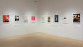 Colorful poster illustrations hang in a horizontal row along the middle of the gallery walls.