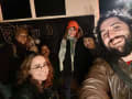 A group of people pose for a photo outside of a bus at night