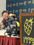 A man leans over a dais laughing