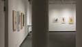 In the back gallery, more collages hang on the walls in rows. Some depict people or faces while others are more abstract designs.