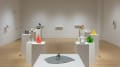 Colorful sculptures arranged on pedestals and wall mounted ledges throughout the SVA Flatiron Gallery space. 
