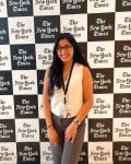 Smiling student poses in front of New York Times black and white checkered background.