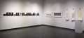 An art exhibit. Art pieces are placed on white walls at head height.
