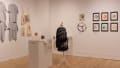 A variety of artworks by Art Therapy students and their clients in gallery space across two intersecting walls.