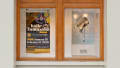 Photograph of street-facing vitrine presenting posters for "Katie Yamasaki, Muralist" and "Chuck's Bucket" exhibitions.