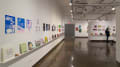 Multiple views of SVA Chelsea Gallery. There is illustrations and paintings hung on the walls. There are multiple shelves throughout the gallery with books places on them.