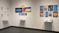 Install image showing an angled view of a corner with three installations of books on shelves with individual pages pinned to the wall.