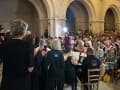  Photograph from behind a choir, looking out onto the seated congregation. 