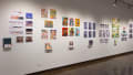 Prints, originals, and books are all displayed on a wall of gallery three.