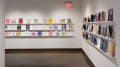 Corner view of gallery four where books are displayed in three rows on shelves across the wall.