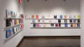 Corner view of colorful books that are displayed in three rows lining the walls of gallery four. 