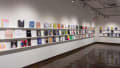 Books are displayed in three rows on long shelves that span the width of gallery four.