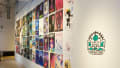 ny posters hang in four rows on a white gallery wall. Each of the posters include illustrated designs and titles. Next to the posters, vinyl on the wall reads “Class of 2024 Animation”.