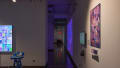 A long hallway to the right of several gallery spaces, with projections and installations visible in the background.