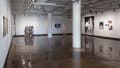 Installation view featuring photographs and photo installations on three walls, with two large white columns in the middle.