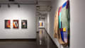 Installation image showing 3 color photographs on the left, a hallway down the middle and a large fabric installation on the right.