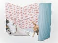 Color photograph of an installation shot from Xunzhen Zhu’s photographic 3D collages series “House Hold”. A collaged domestic scene combined photographs of blue curtain, pink floral bed sheets, window sill and a cat.  				