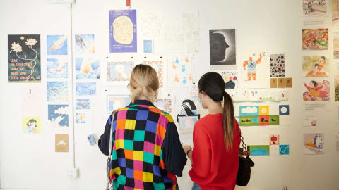 Two people looking at a wall of illustrations