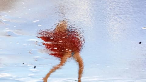 The mood is electric. Shimmering/Floating/Moving dancing red skirt in the process of dissolving above a pair of brown legs that look almost like stick figure that are also in the process of dissolving. It’s all against a light blue background of what seems to be a water of sky/foam/cloud.