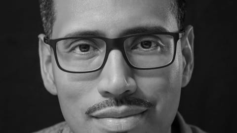 Black and white image of Nery Lemus, a man with glasses looking directly at the camera with a subtle smile