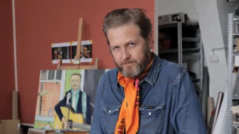 Image of Ragnar Kjartansson in his studio with a figure painting of a person playing guitar in the background