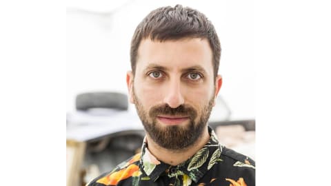 A headshot of a man with brown short hair and a goatee and beard looking at the camera 