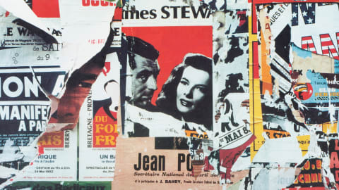 Remnants of torn posters from the 50s or 60s with text written in French, one of which includes a partial photograph of actor Jimmy Stewart.