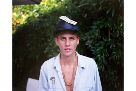 Person wearing black hat with hand-written note reading "Jock Strap Collector"