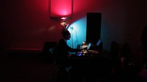 A man working on a computer in a dark room accented with red and blue light.